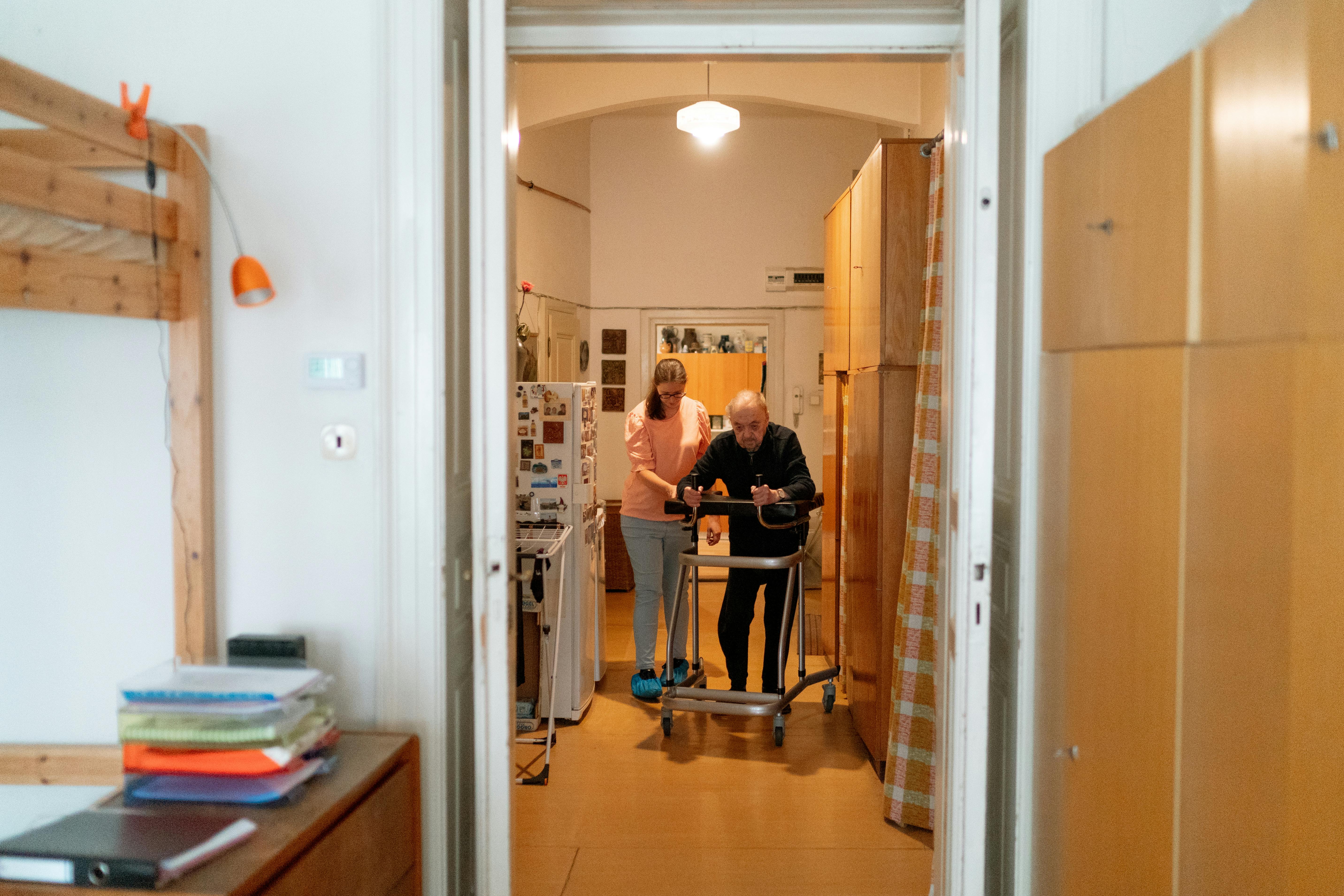 Caregiver assisting an older adult with a walker at home