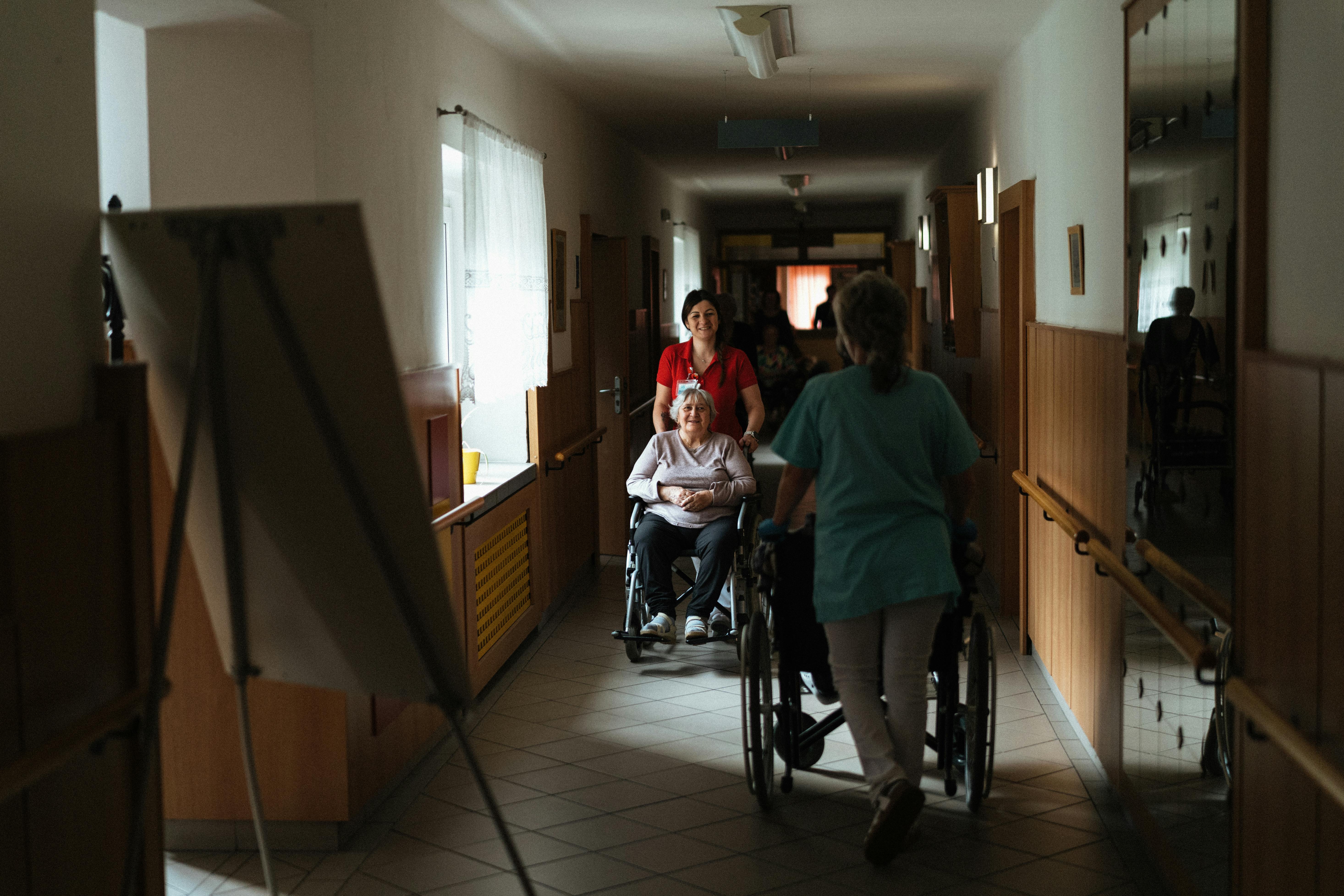 Caregivers supporting residents in a facility hallway